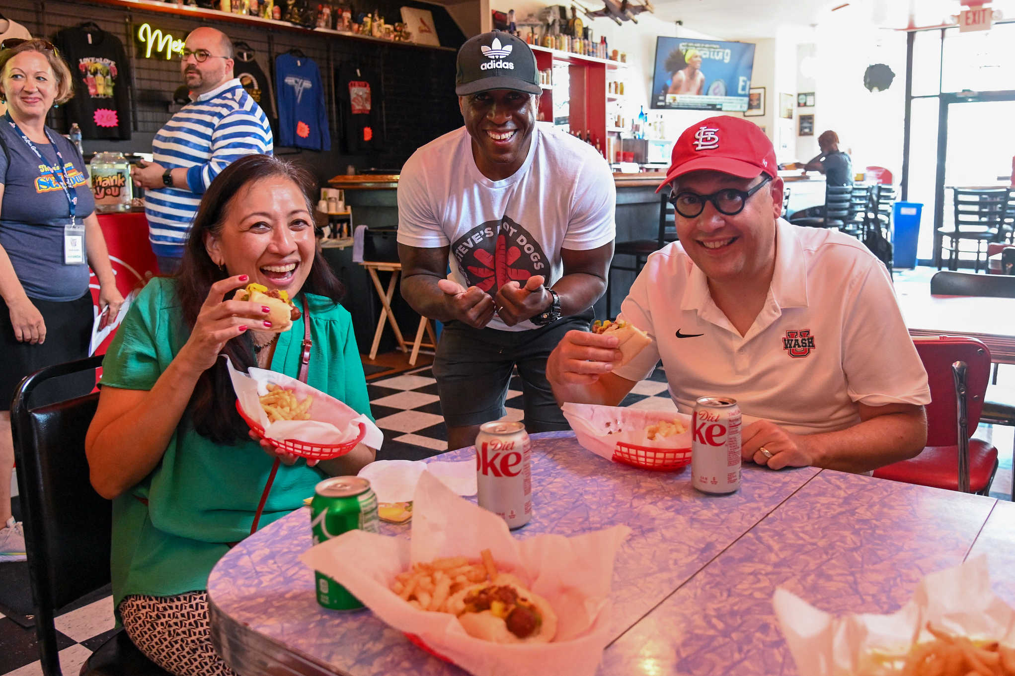 Chancellor Andrew D. Martin and Vice Chancellor Anna Gonzalez sit at a table enjoying food with restaurant owner Steve Ewing